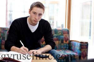 A young man working on his science physics or math homework in an educational setting.