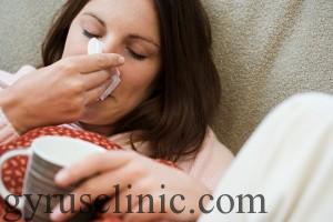 Woman with tissue and hot drink --- Image by © Royalty-Free/Corbis